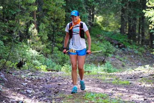 a woman is running in the woods on a trail.