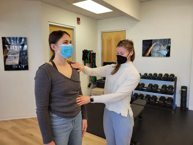 two women in a gym wearing face masks.