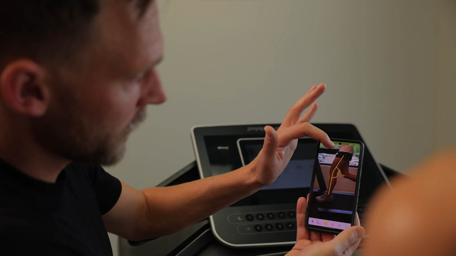 Therapist analyzing a runner’s form using slow-motion video footage during a gait analysis session, highlighting detailed movement insights for optimized performance and injury prevention.